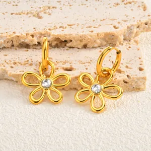Gros plan de boucles d'oreilles fleurs dorées ajourées avec cristal sur pierre naturelle