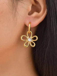 Détail d'une boucle d'oreille fleur dorée avec zircon central portée par un mannequin