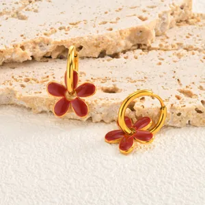 Gros plan détaillé des boucles d'oreilles en acier doré avec pendentifs fleurs rouges