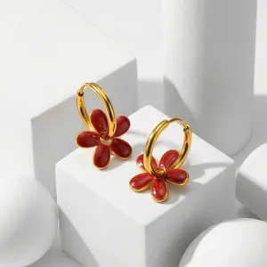 Gros plan détaillé de boucles d'oreilles créoles dorées avec fleurs rouges ajourées
