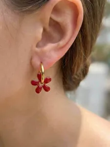 Gros plan détaillé d'une boucle d'oreille fleur rouge émaillée avec anneau doré