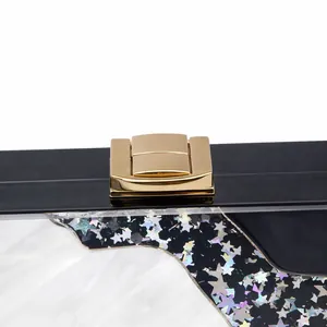 Detail of acrylic clutch with colorful star sequins and golden metal closure clasp