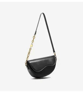 Close-up of black saddle bag featuring unique wavy bottom and gold metal chain strap