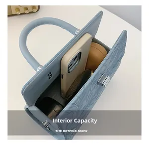 Internal capacity of light blue floral embossed handbag showing phone and cosmetics