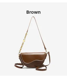 Close-up of brown leather saddle bag with unique flap design and gold chain lock strap