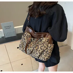 Détail du grand sac cabas léopard avec lanières en cuir marron porté à l'épaule