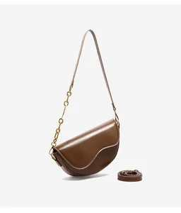 Detail view of brown saddle bag with wavy flap design and gold chain link strap