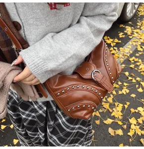Détail du sac bandoulière en cuir marron avec clous argentés et boucles en décor d'automne