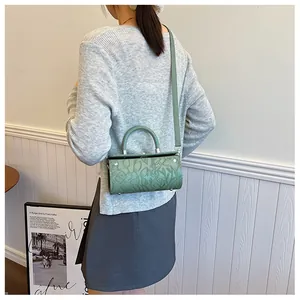 Model wearing a grass green cylindrical barrel bag with floral 3D embossing details