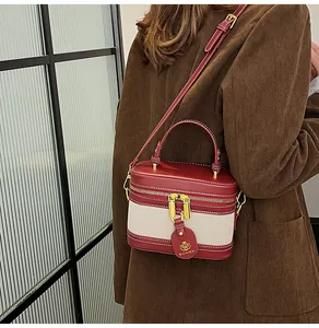 Dettaglio della borsa patchwork bordeaux e crema con finiture dorate e logo tag