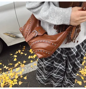 Sac demi-lune en cuir marron avec clous argentés porté sur l'épaule en automne