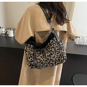 Détail du sac cabas en toile léopard avec poignées en cuir noir et bandoulière réglable