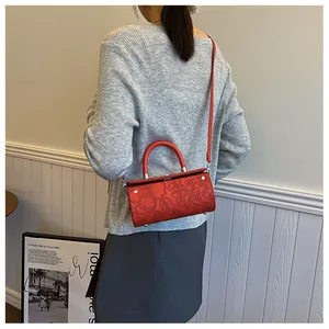 Model showing red cylindrical barrel bag with floral embossing and top handle