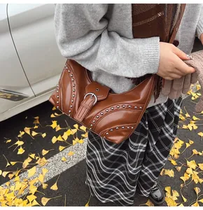 Détail d'un sac demi-lune marron avec rivets argentés dans une scène de rue automnale