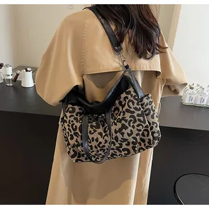 Sac hobo chic à motif léopard avec lanières en cuir noir porté sur un trench kaki