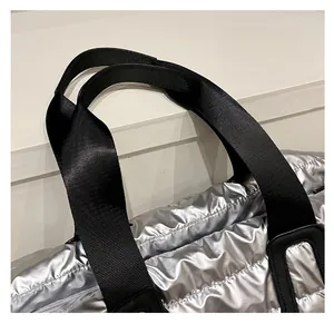 Détail des poignées en nylon noir renforcé sur un sac cabas argenté métallisé matelassé