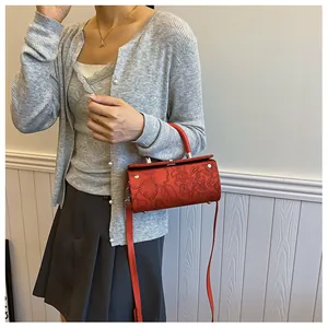 Detailed view of red cylindrical bag with embossed floral texture and silver hardware