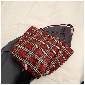 Macro shot of red and cream plaid tote bag fabric with vintage oval metal logo plaque