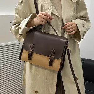 Vintage two-tone faux leather satchel bag worn over a trench coat for a chic look