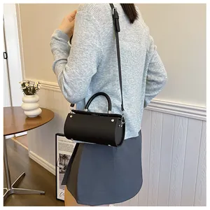 Fashionable black cylinder bag with embossed leather texture and silver studs on side