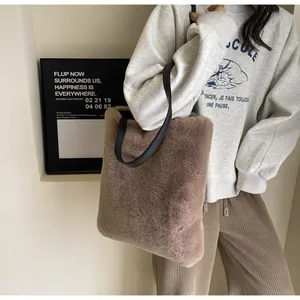 Sac fourre-tout en fausse fourrure taupe porté à l'épaule avec une bandoulière noire