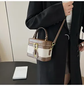 Dettaglio borsa vintage in pelle marrone e tela indossata da una modella