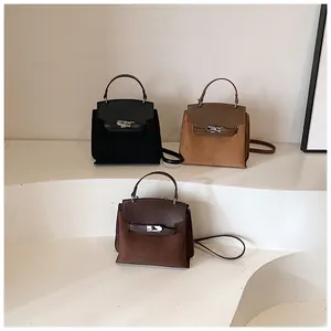 Suede and leather Kelly style bags in black, camel, and dark brown on display steps