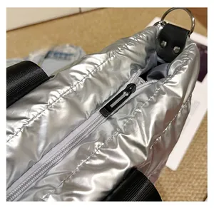 Détail du sac argenté métallisé avec fermeture éclair noire fluide et anneau en D