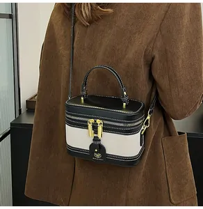 Dettaglio di cuciture a contrasto e finiture dorate su una piccola borsa a tracolla box
