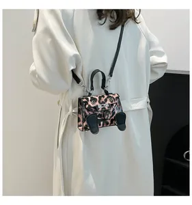 Rear view of a model wearing the mini leopard print crossbody bag with foot charms