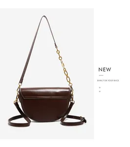Detail of dark brown saddle bag with matte leather and elegant gold chain strap