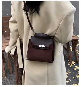 Detail of dark brown matte leather handbag with metallic clasp in an autumn park setting