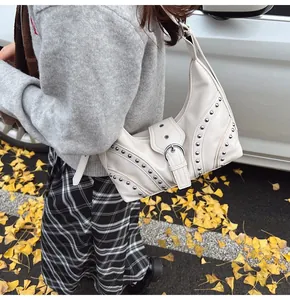 Détail du sac demi-lune en PU crème avec rivets argentés porté par un mannequin en automne