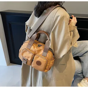 Detail view of khaki nylon crossbody bag with multi-pocket design and wide fabric strap
