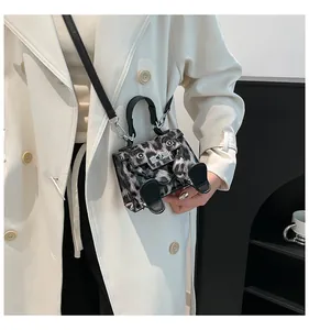 Detail of creative leopard print mini bag with black legs on a beige trench coat