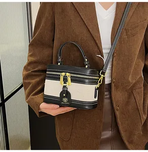 Dettaglio di una borsa a cilindro in tela e pelle con finiture e catena dorate