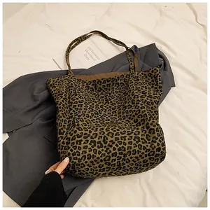 Detailed view of the large leopard print tote bag placed on a grey blazer and white bedding