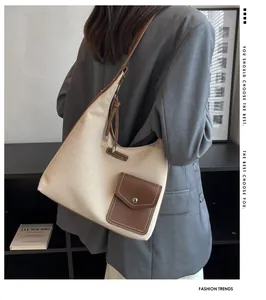 Détail du sac seau en toile avec garniture en cuir marron porté par un mannequin
