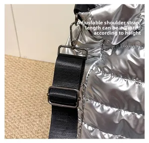 Détail de la bandoulière noire réglable avec boucle en métal sur un sac argenté brillant