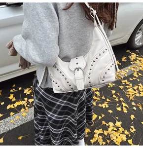 Détail du sac croissant crème avec rivets argentés et boucle en décor d'automne