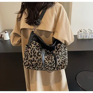 Gros plan d'un sac cabas léopard avec lanières en cuir noir porté par un mannequin en trench