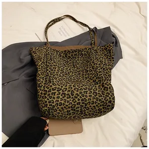 Detailed view of leopard print tote bag placed on white fabric and grey blazer