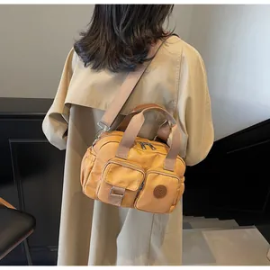 Detail view of the multi-pocket canvas crossbody bag showing texture and strap in camel yellow