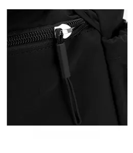 Close-up of smooth silver metal zipper and black nylon fabric on a casual shoulder bag