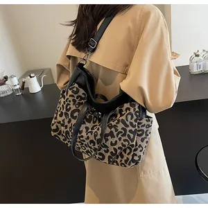Détail d'un sac cabas tissé léopard avec anses en cuir sur un mannequin portant un trench-coat
