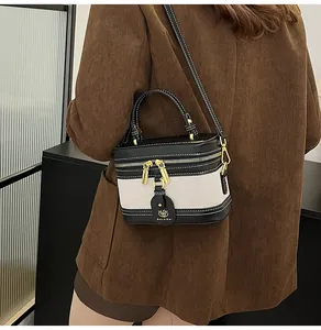 Dettaglio borsa a scatola vintage in tela beige con finiture in pelle nera e dettagli oro