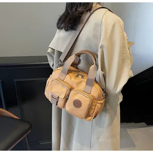 Khaki canvas crossbody bag with multiple front pockets and adjustable strap shown on model