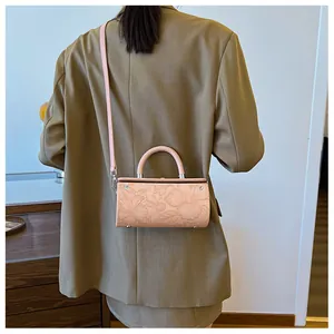 Detail of pink cylindrical box bag with floral embossed leather and detachable strap