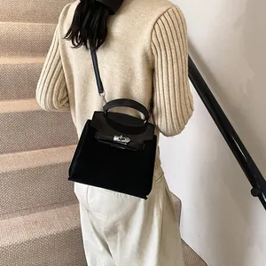 Side view of model carrying a black frosted texture trapezoid handbag on stairs
