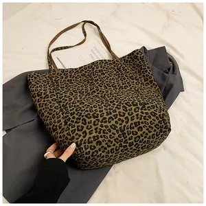 Flat lay view of a large leopard print tote bag placed over a stylish grey blazer